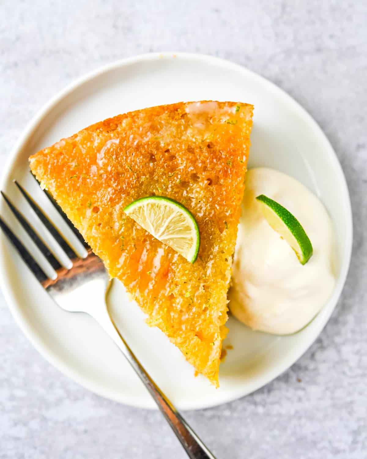 A slice of mango cake with lime glaze and whipped cream. 