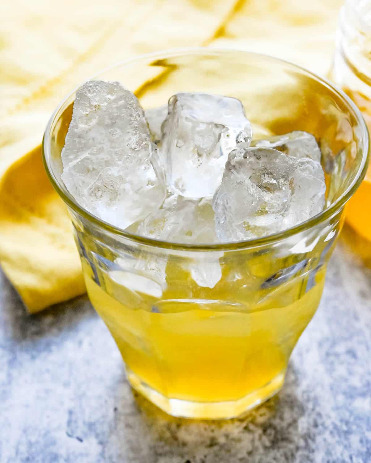 Adding passion fruit syrup and lemon juice to an ice-filled glass.