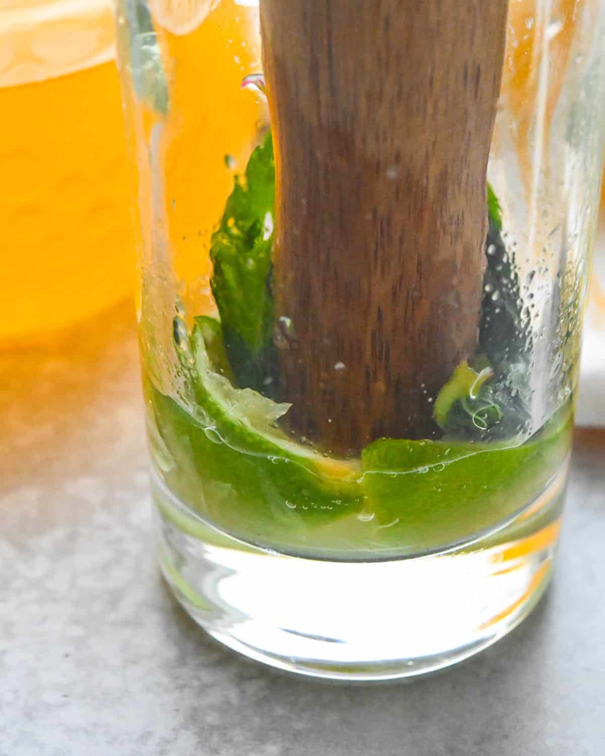 muddling mint and lime leaves in a glass.
