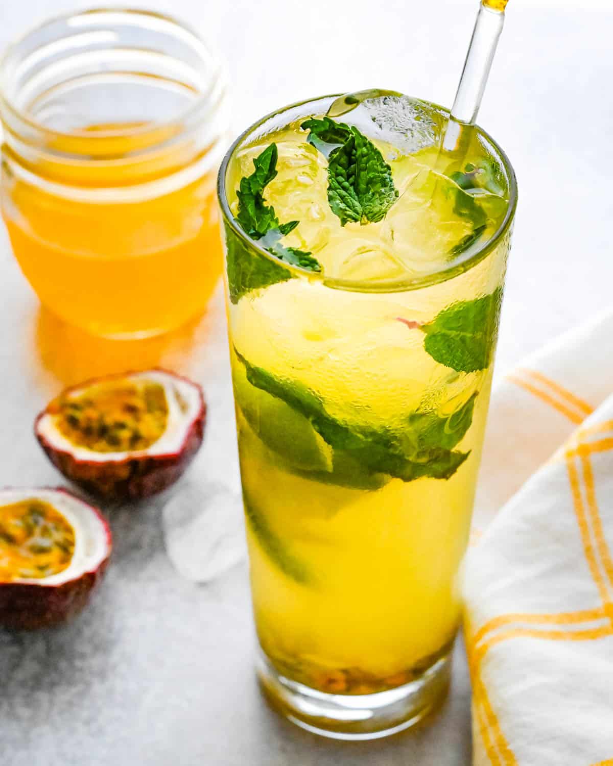 A tall glass of passion fruit mojito with fresh mint and lime.