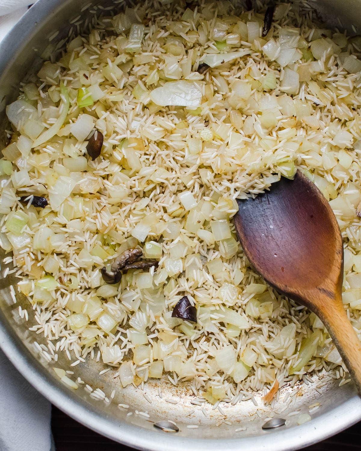 Adding onions and rice to the skillet.