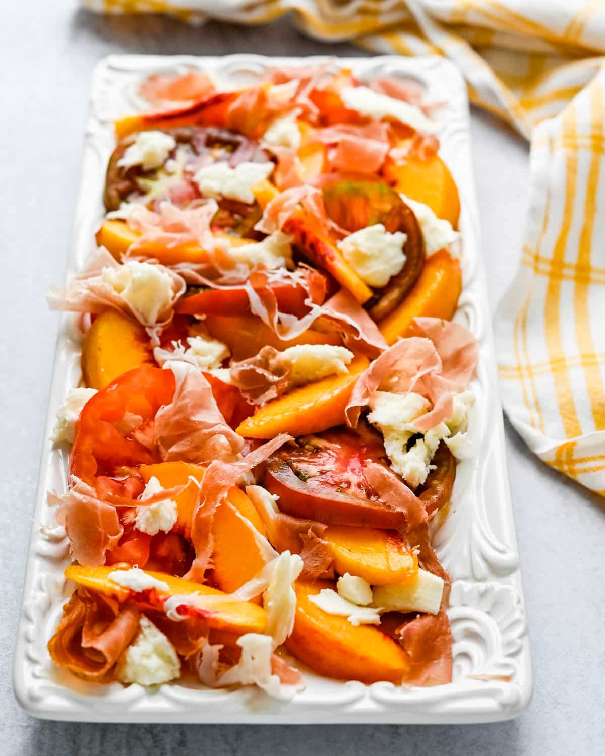 Arranging the peaches, heirloom tomatoes, mozzarella cheese and prosciutto on a platter.