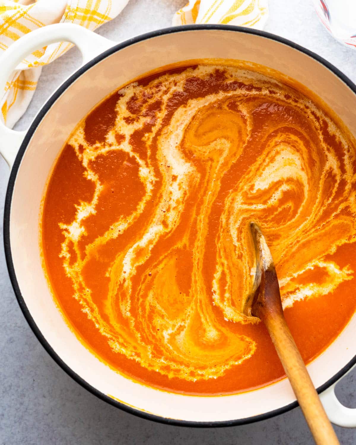stirring cream into a pot of tomato soup.
