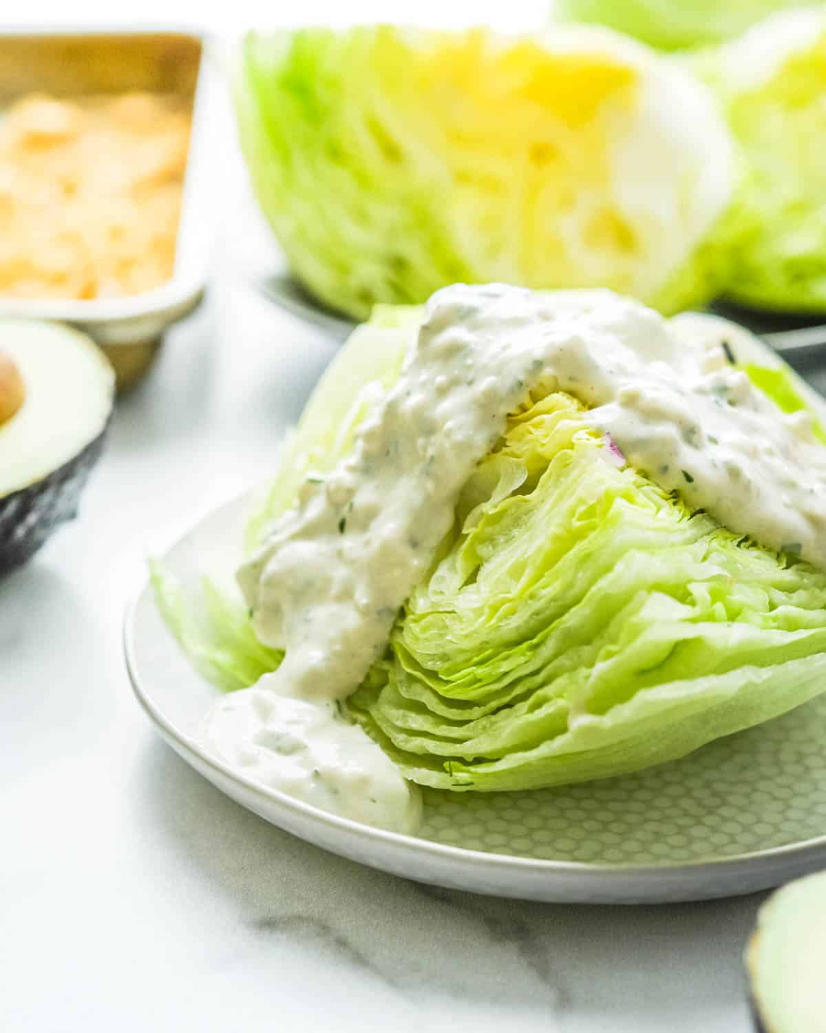 Adding a ladle of blue cheese dressing to a wedge of iceberg lettuce.