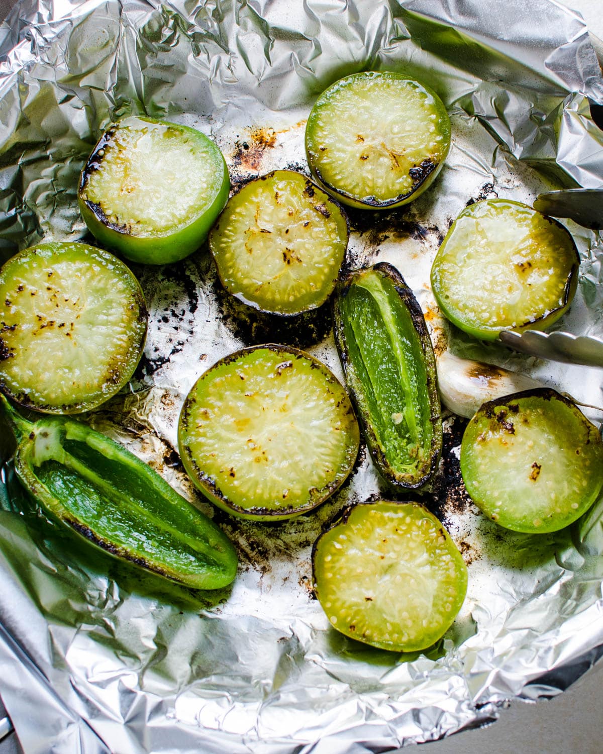 Cooking the tomatillos, garlic and jalapenos in a skillet covered with foil.