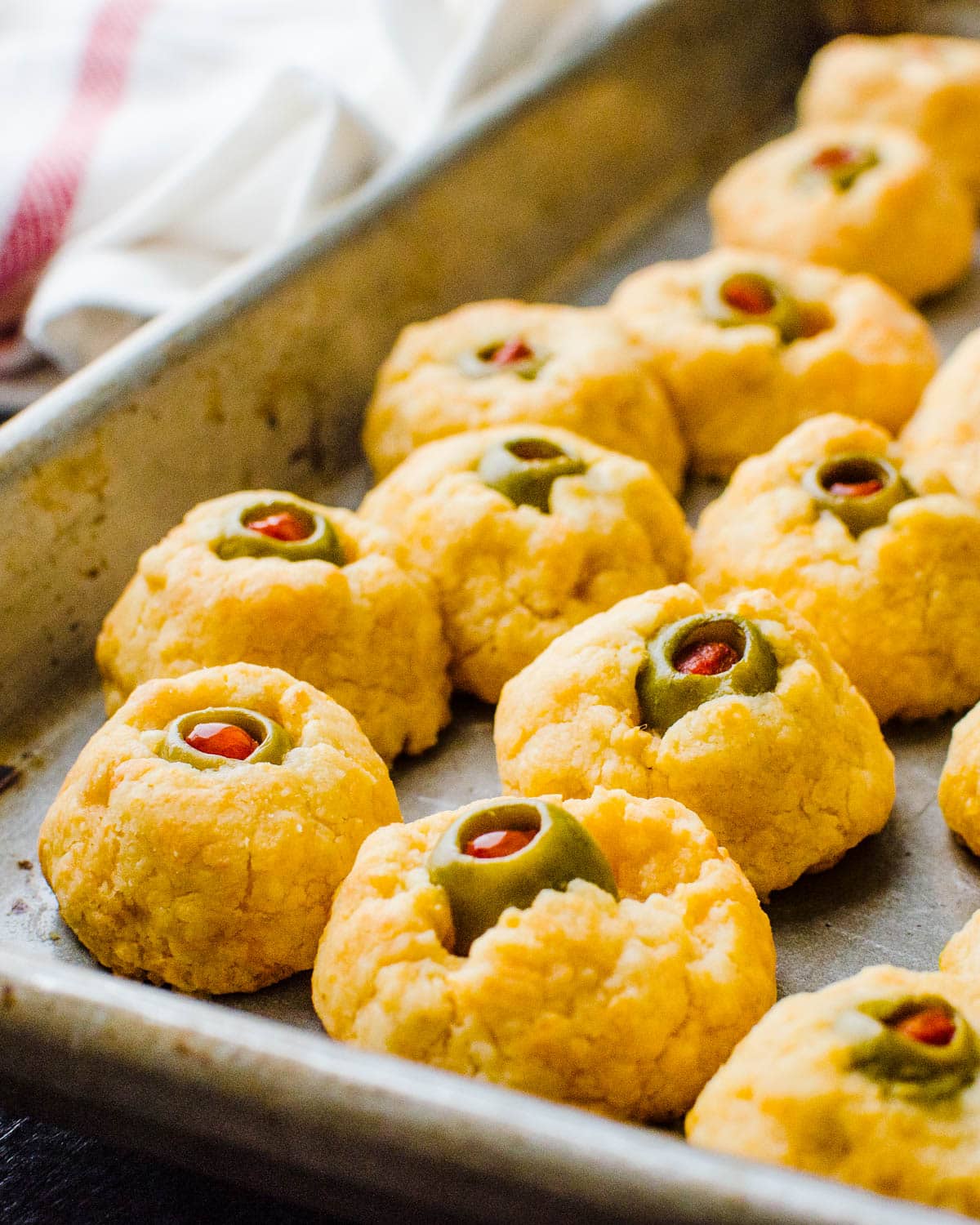 Baked cheese olive eyeballs on a sheet pan.