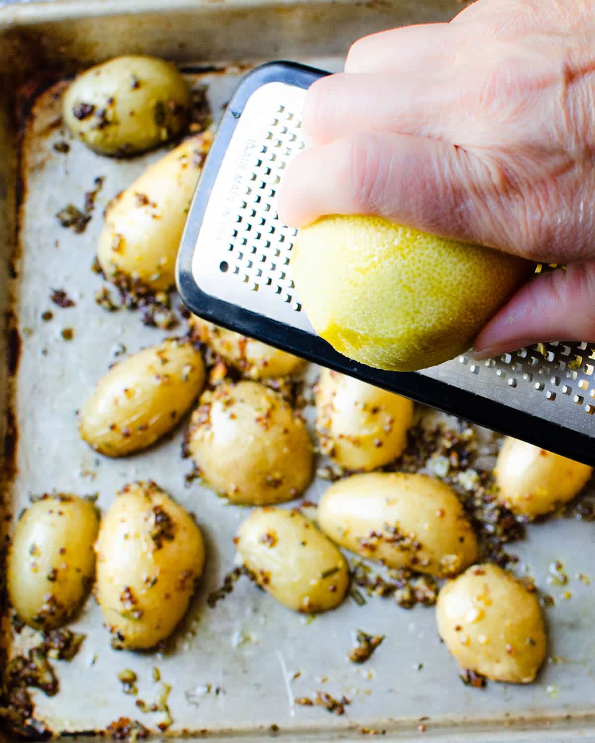 Adding lemon zest to roasted potatoes.
