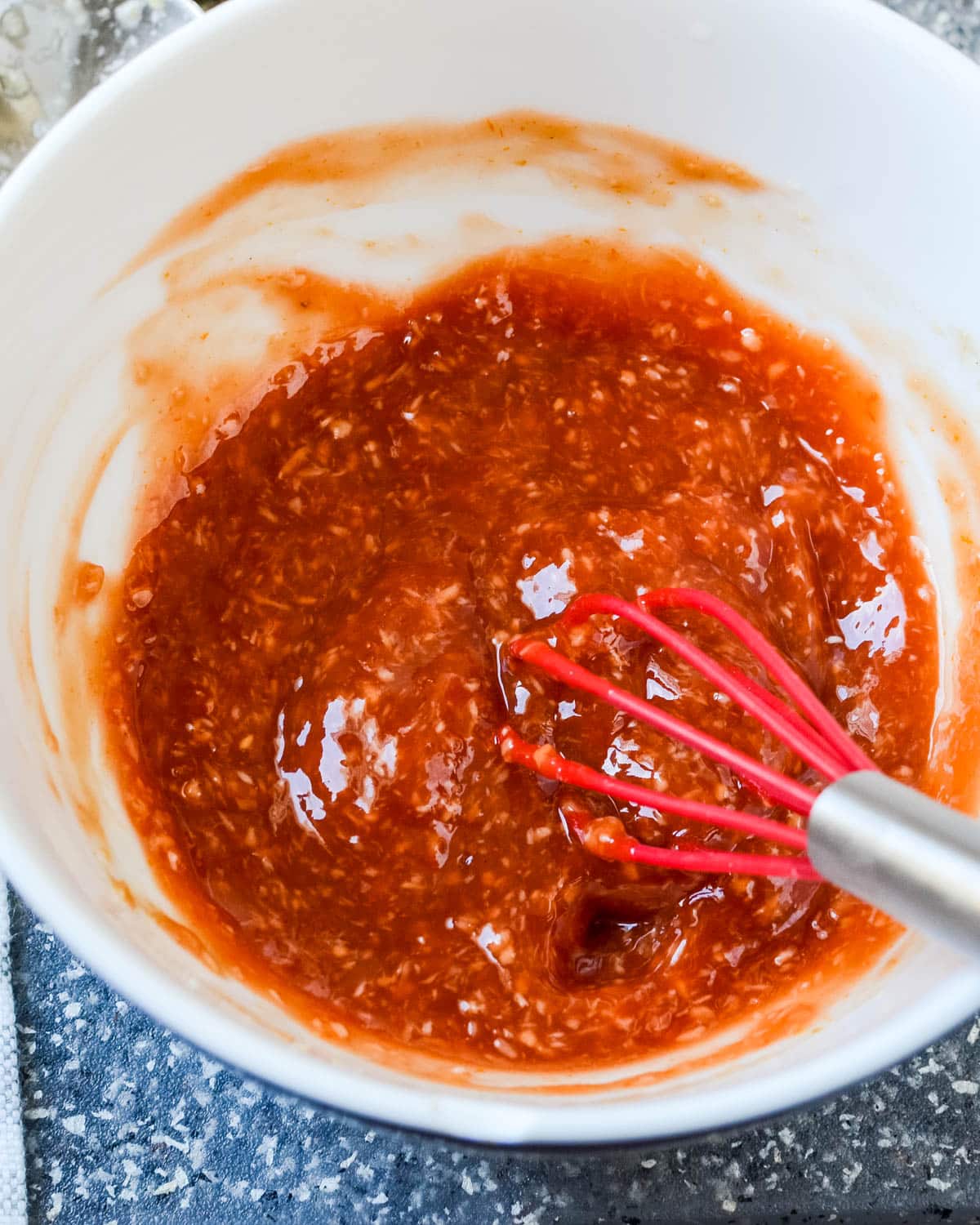 mixing the spicy cocktail sauce with a whisk.