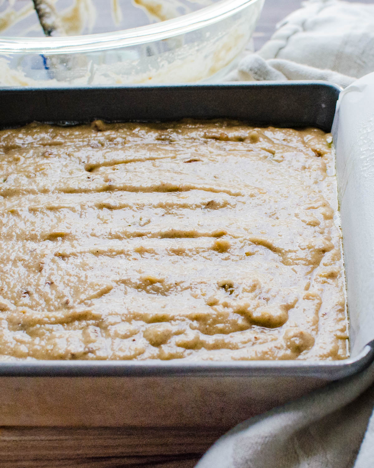 Pouring applesauce cake batter into the cake pan.