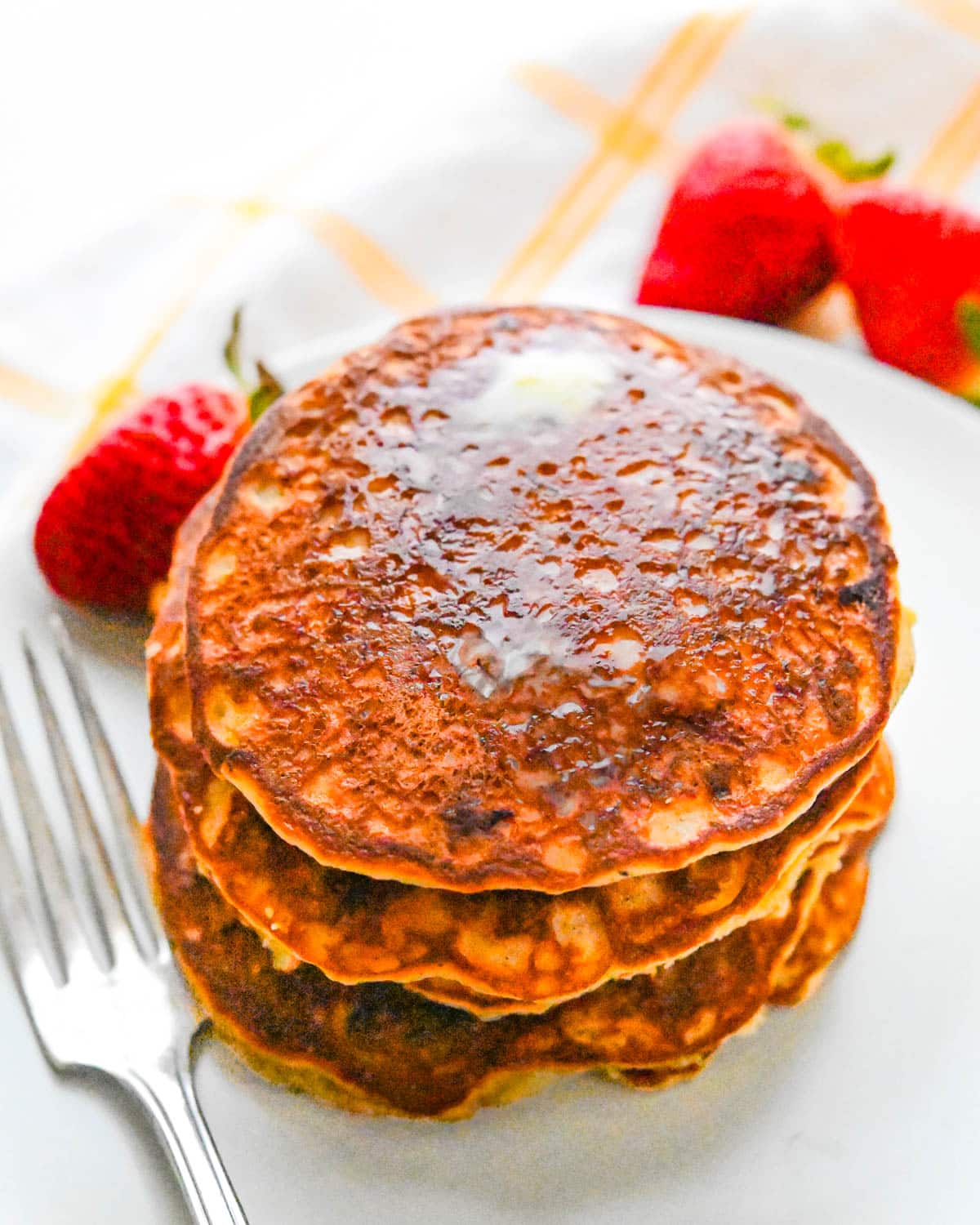 A stack of almond flour banana pancakes on a plate with strawberries.