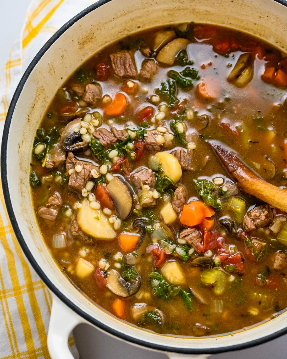 a pot of beef barley soup with vegetables.