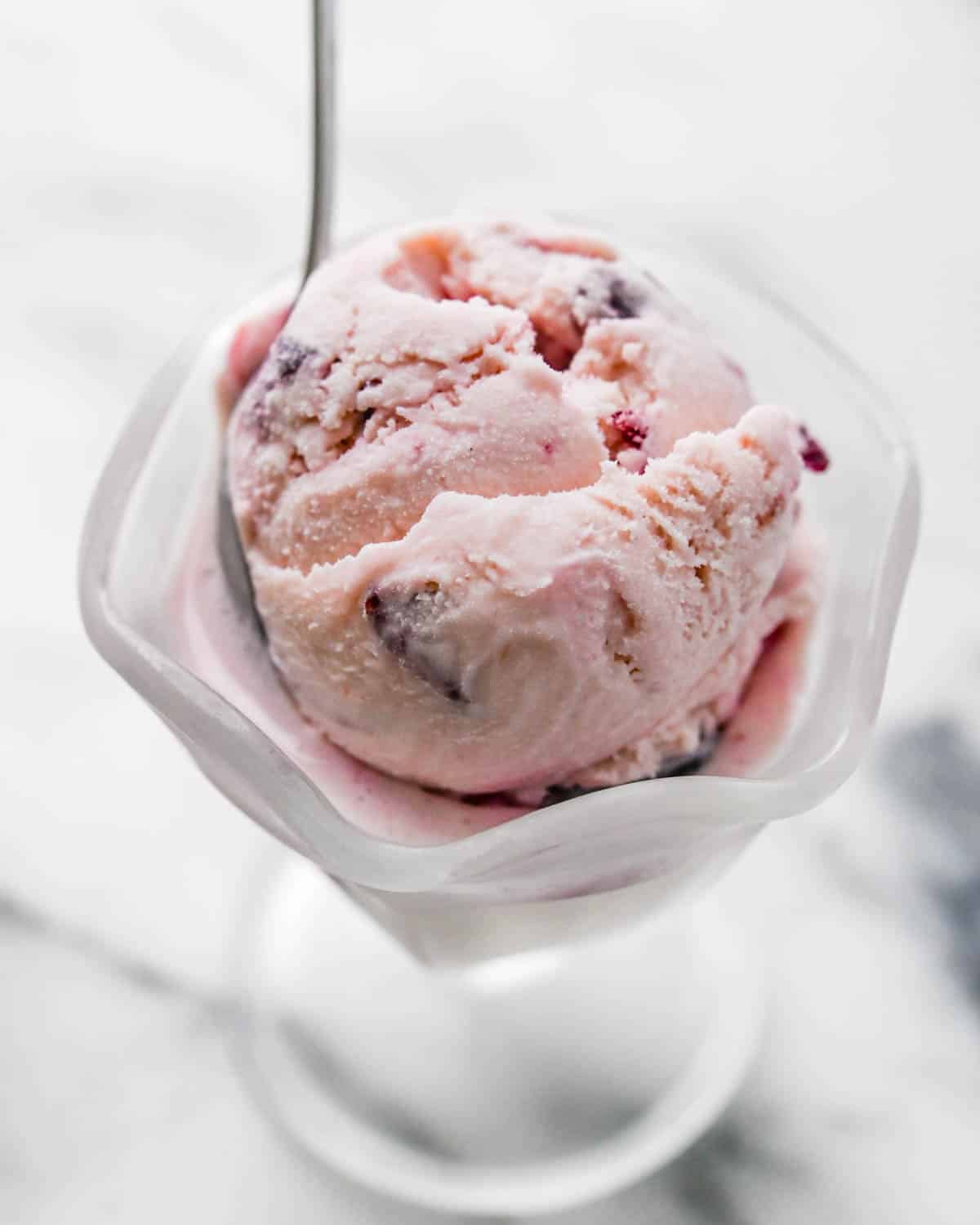 A dish of cherry ice cream with a spoon.