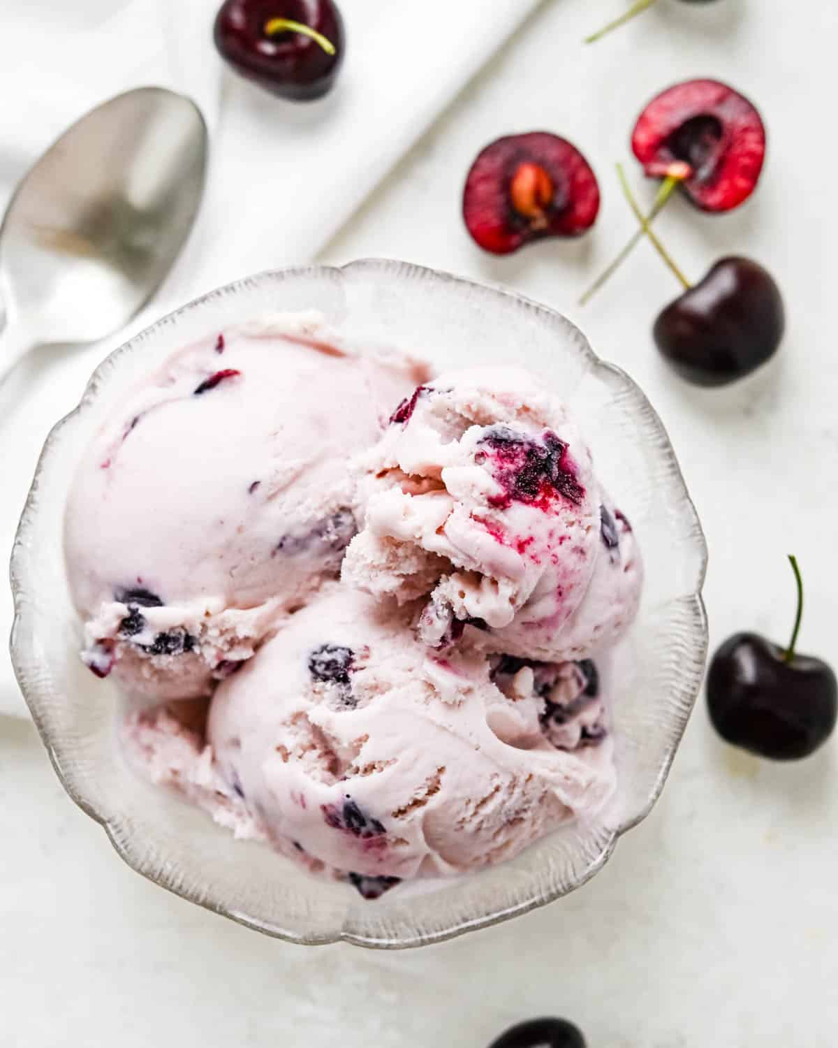 Three scoops of cherry ice cream in a glass bowl.