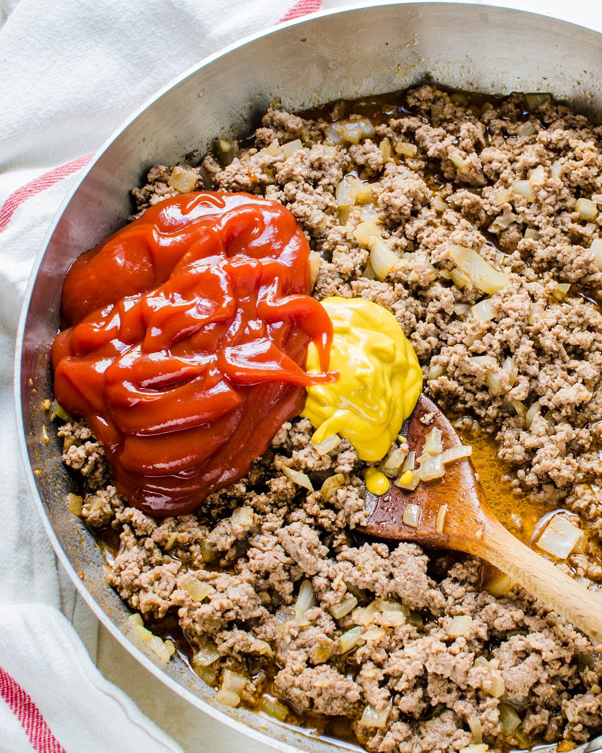Adding ketchup and mustard to the ground beef mixture.