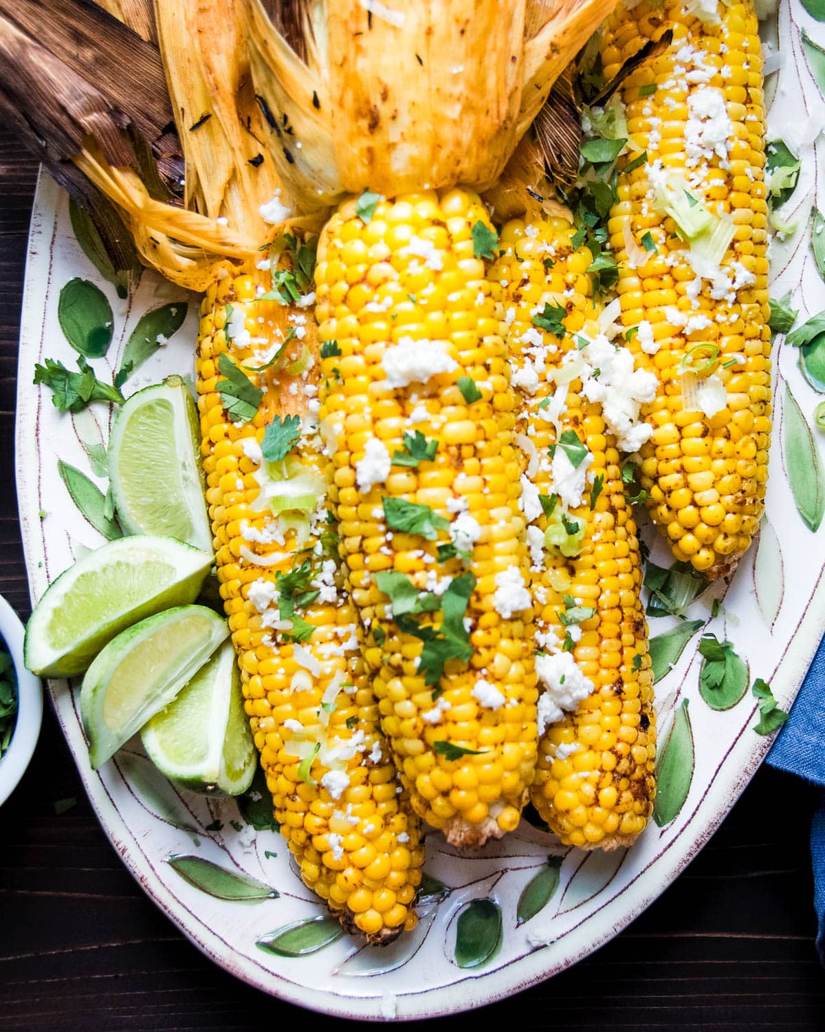 Peel back the husks and serve the chipotle corn on the cob with queso fresco, green onion and fresh cilantro.