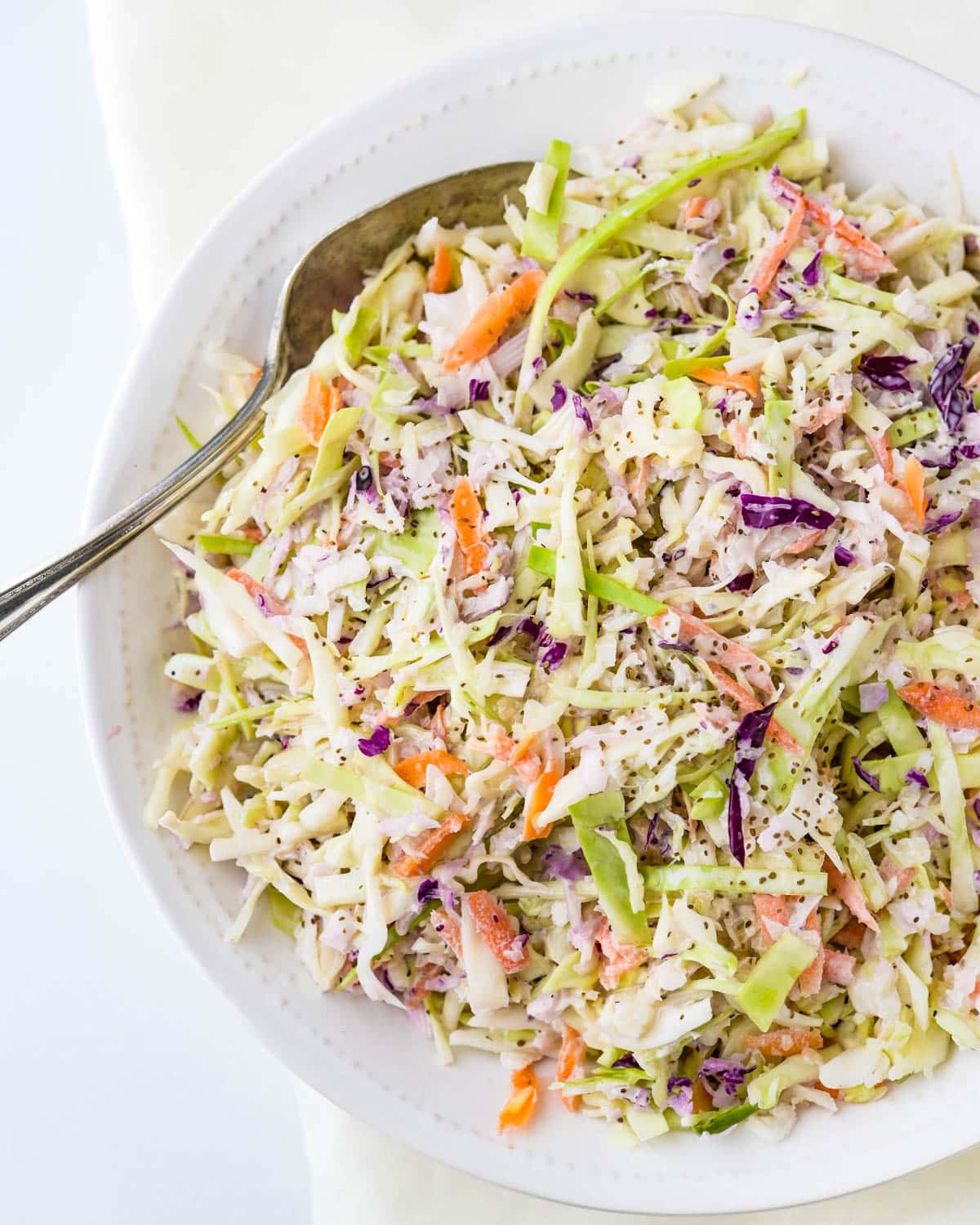 Serving coleslaw in a white serving bowl.