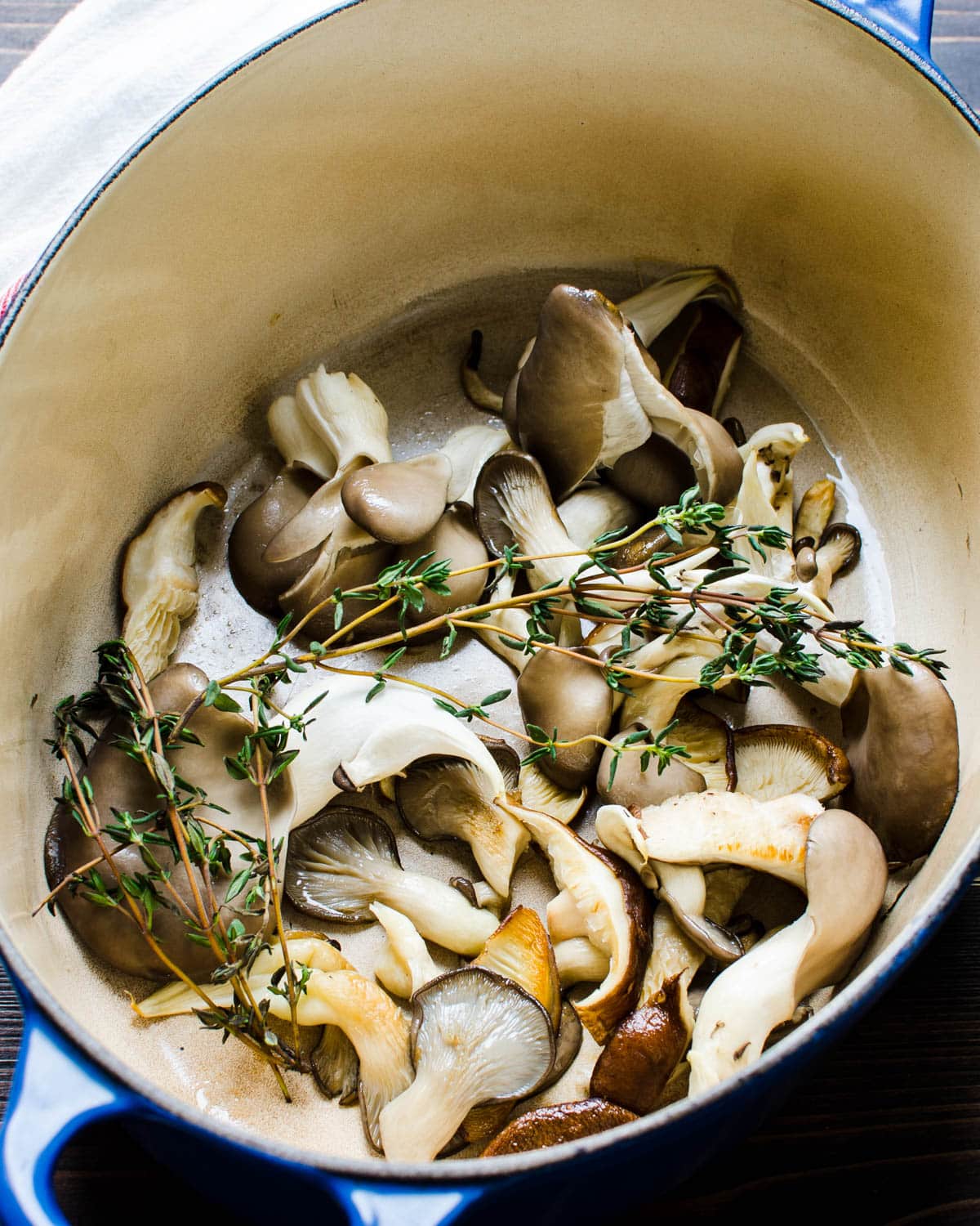 Cooking the mushrooms in a dutch oven with thyme.