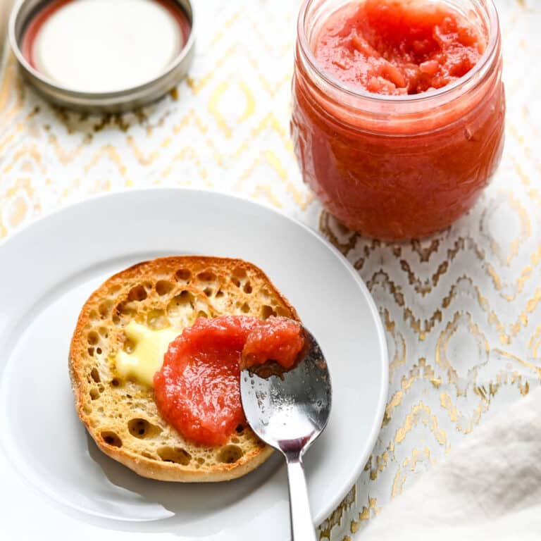 Spreading homemade guava jam on a toasted English muffin for breakfast.