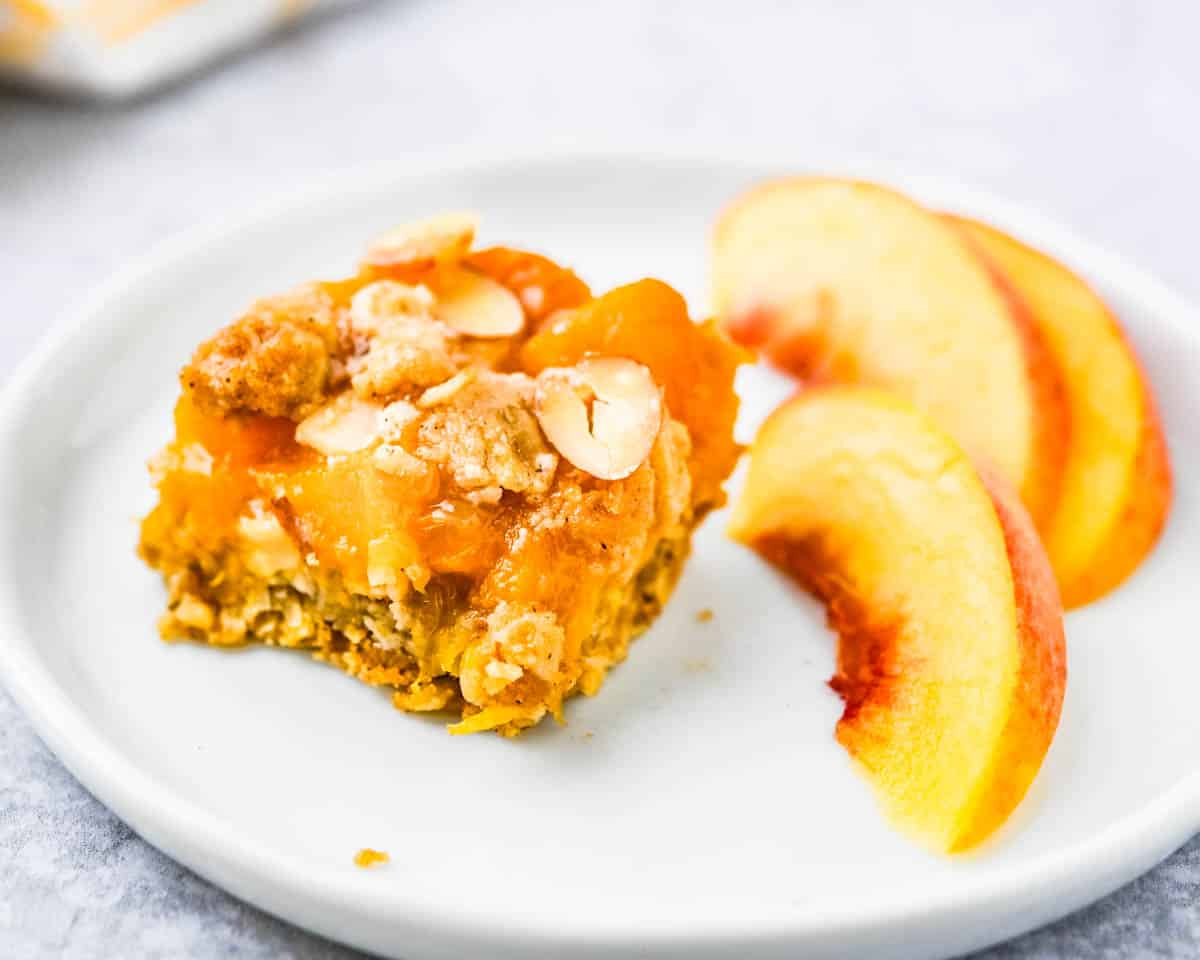 Serving a peach bar on a plate with a side of fresh peaches.