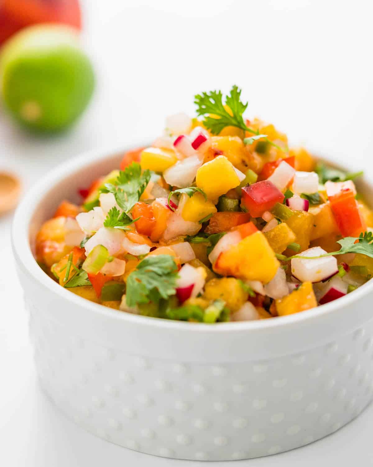 A white serving dish filled with fresh peach salsa.