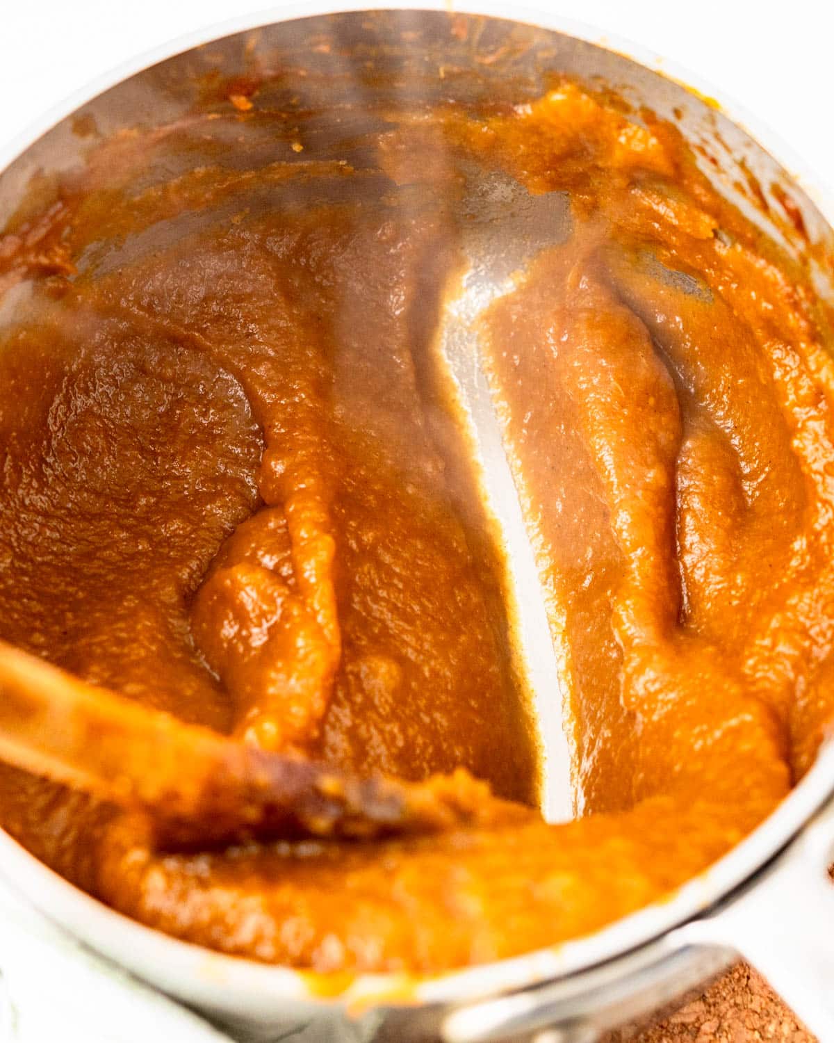 I am running a wooden spoon along the bottom of the pot to see if the pumpkin butter is ready.