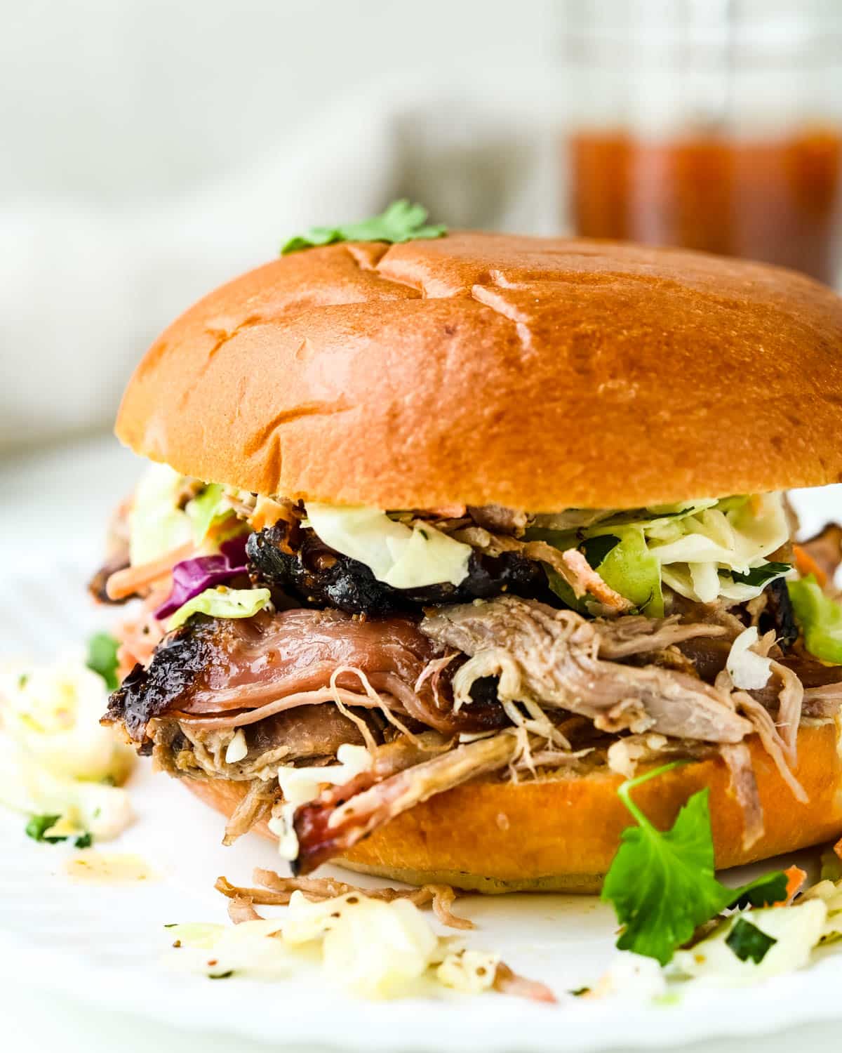 A messy pulled pork sandwich piled with coleslaw.
