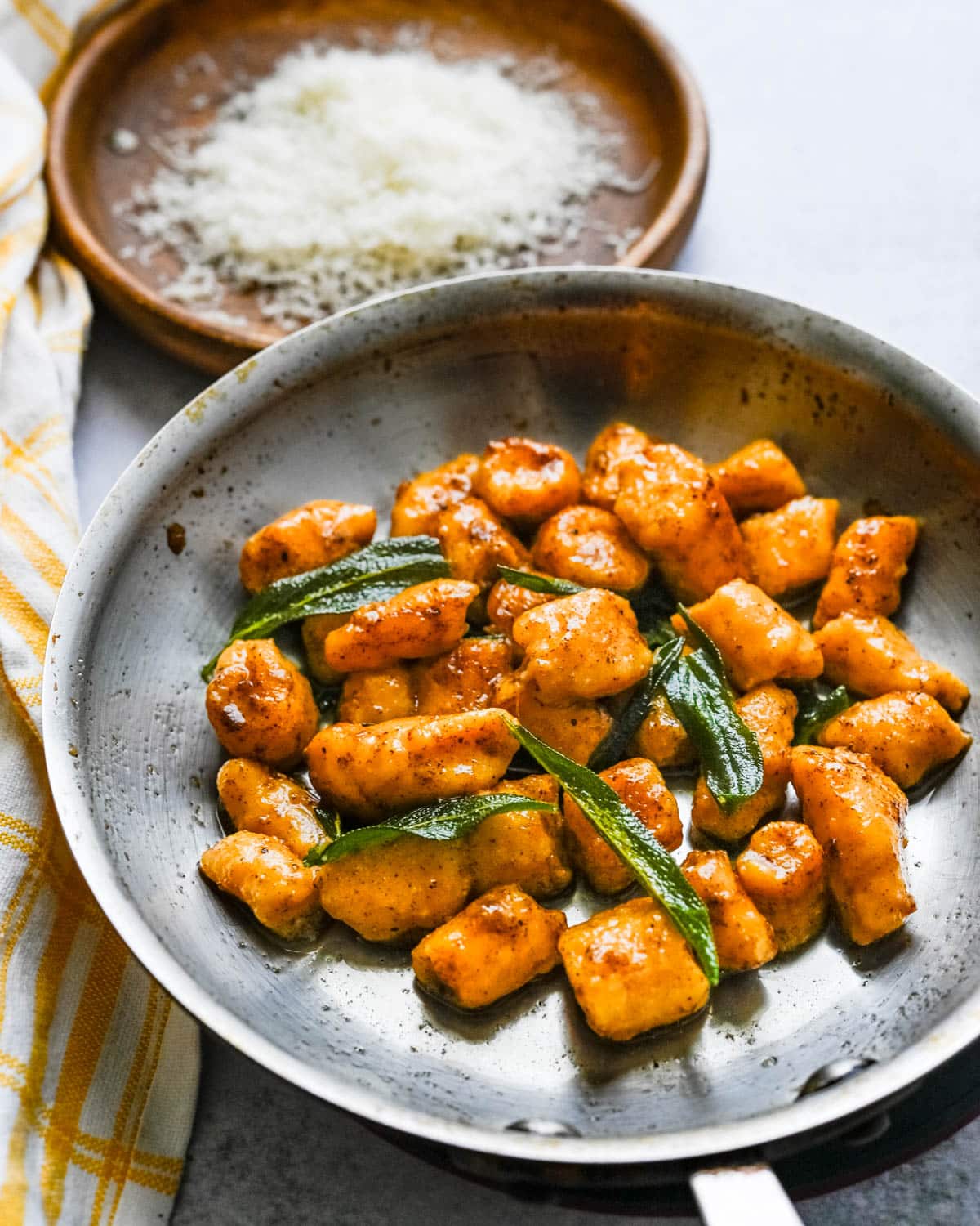 Adding crispy sage leaves and fresh grated parmesan cheese to the sweet potato gnocchi.