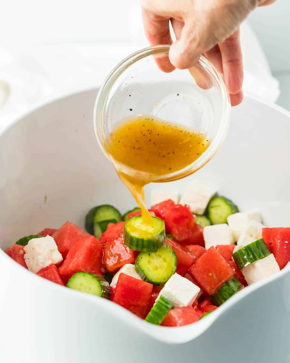 Pouring honey lime dressing over watermelon salad. 