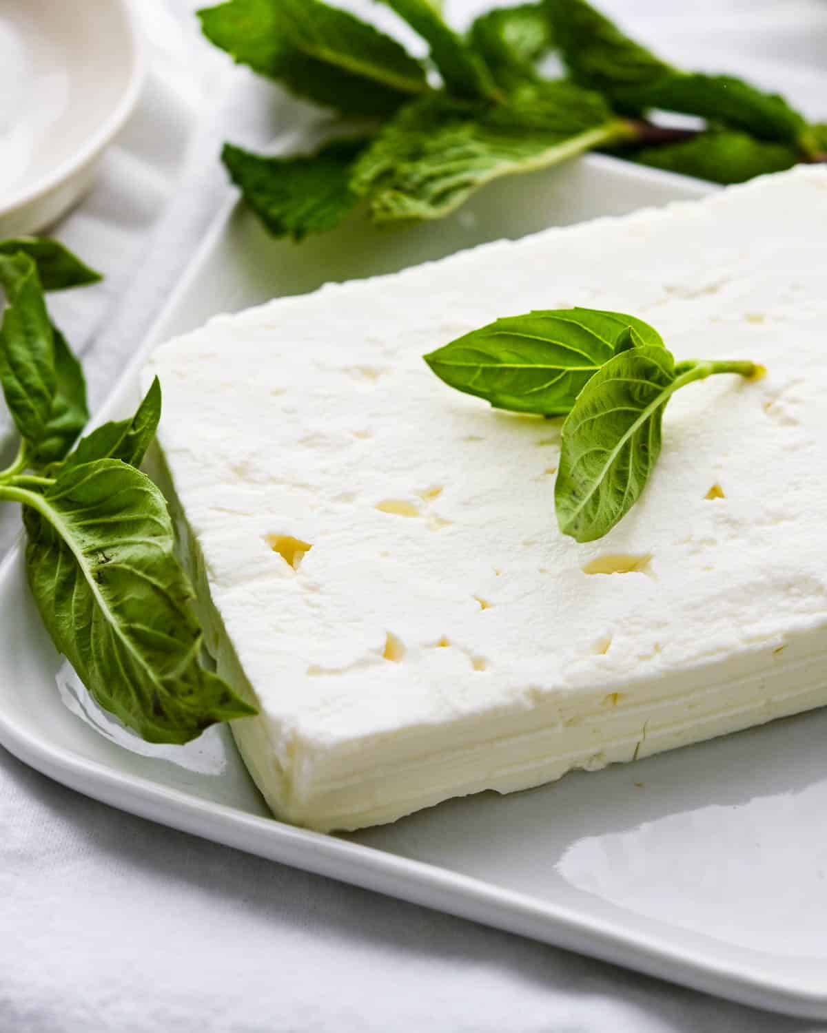 A block of feta cheese with fresh basil and 