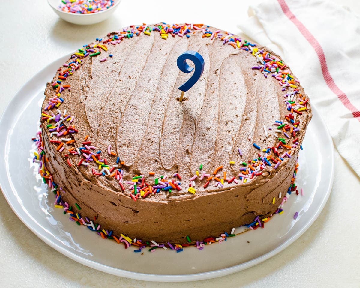 a frosted yellow cake decorated with sprinkles for a birthday.
