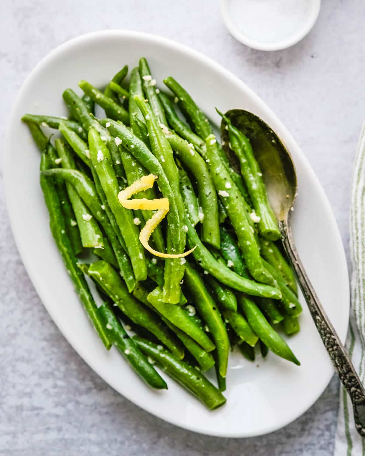 Serving a dish of garlic lemon green beans on a white serving dish.