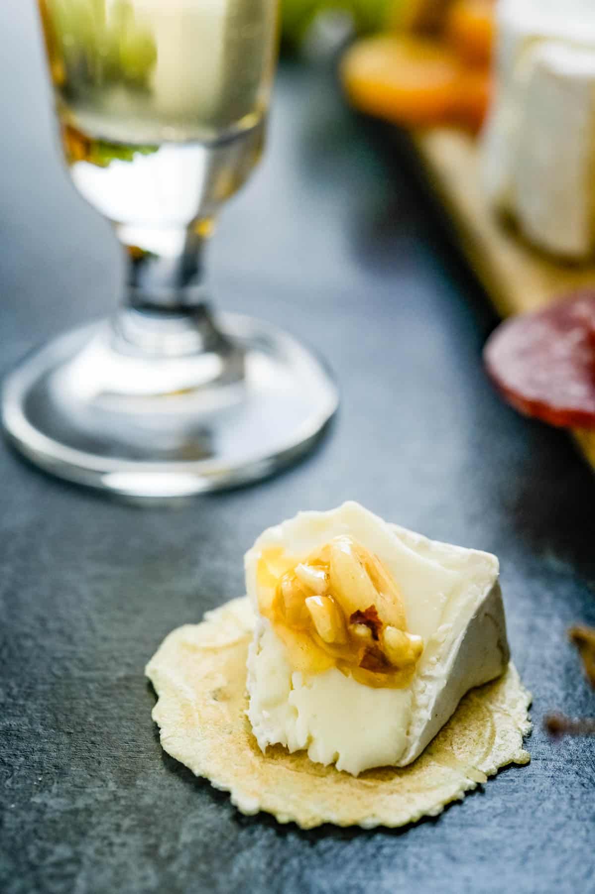 Cheese and crackers next to a glass of wine.