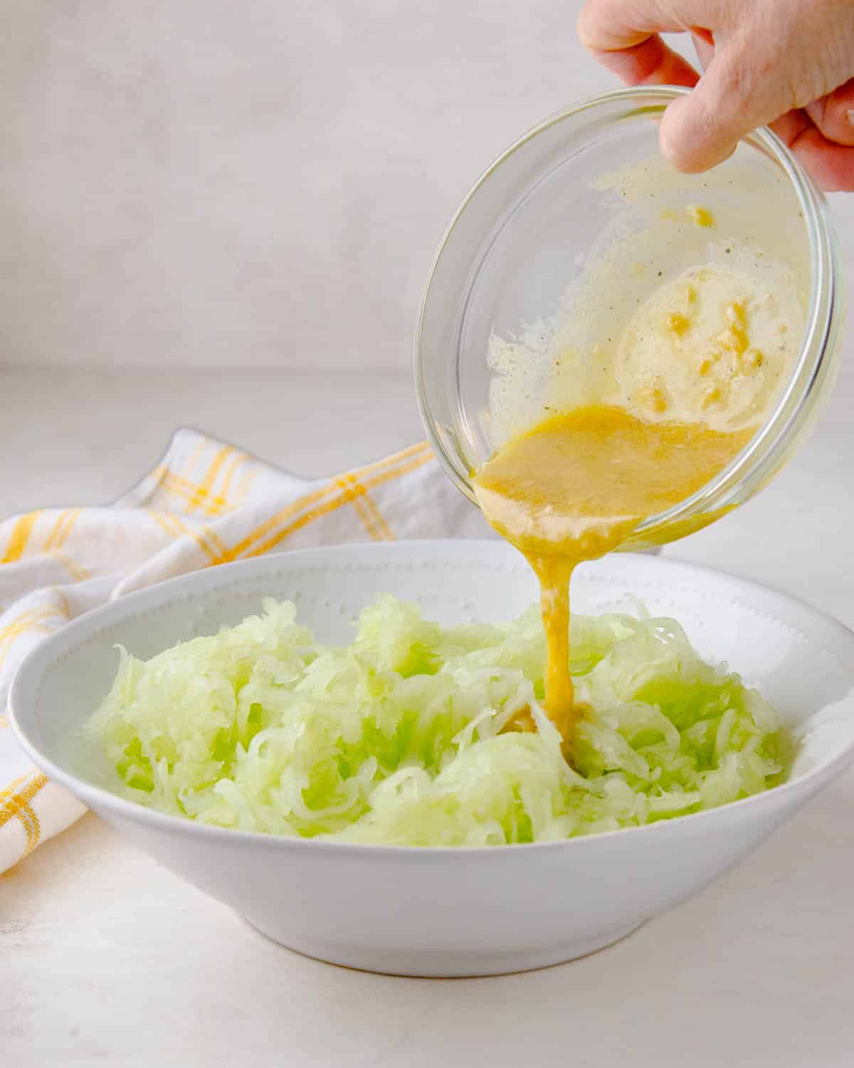 Adding dressing to the grated cucumber.