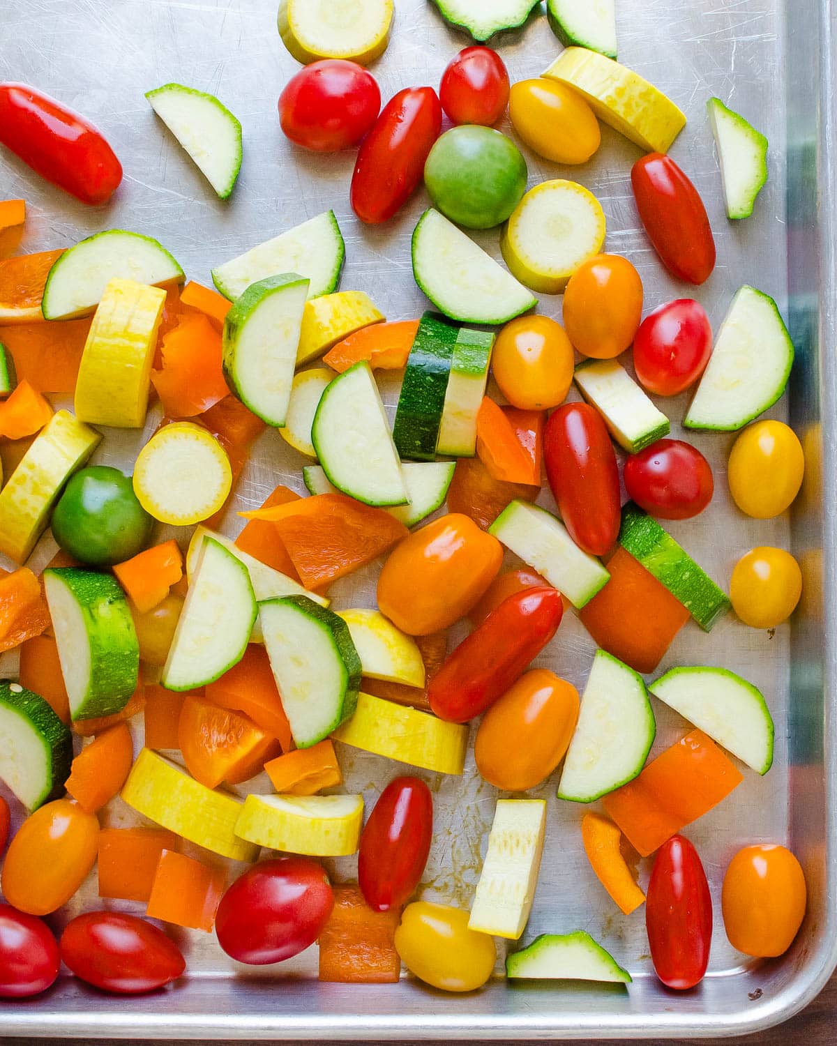 Zucchini, squash, peppers and grape tomatoes on a sheet pan.