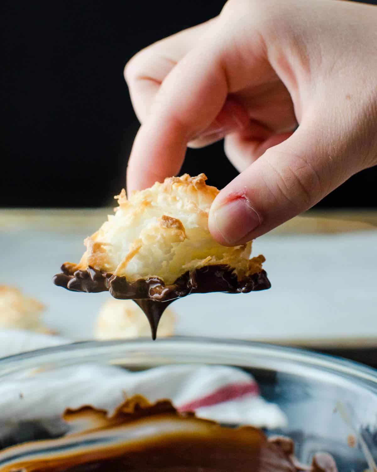 Dipping the macaroons in chocolate.