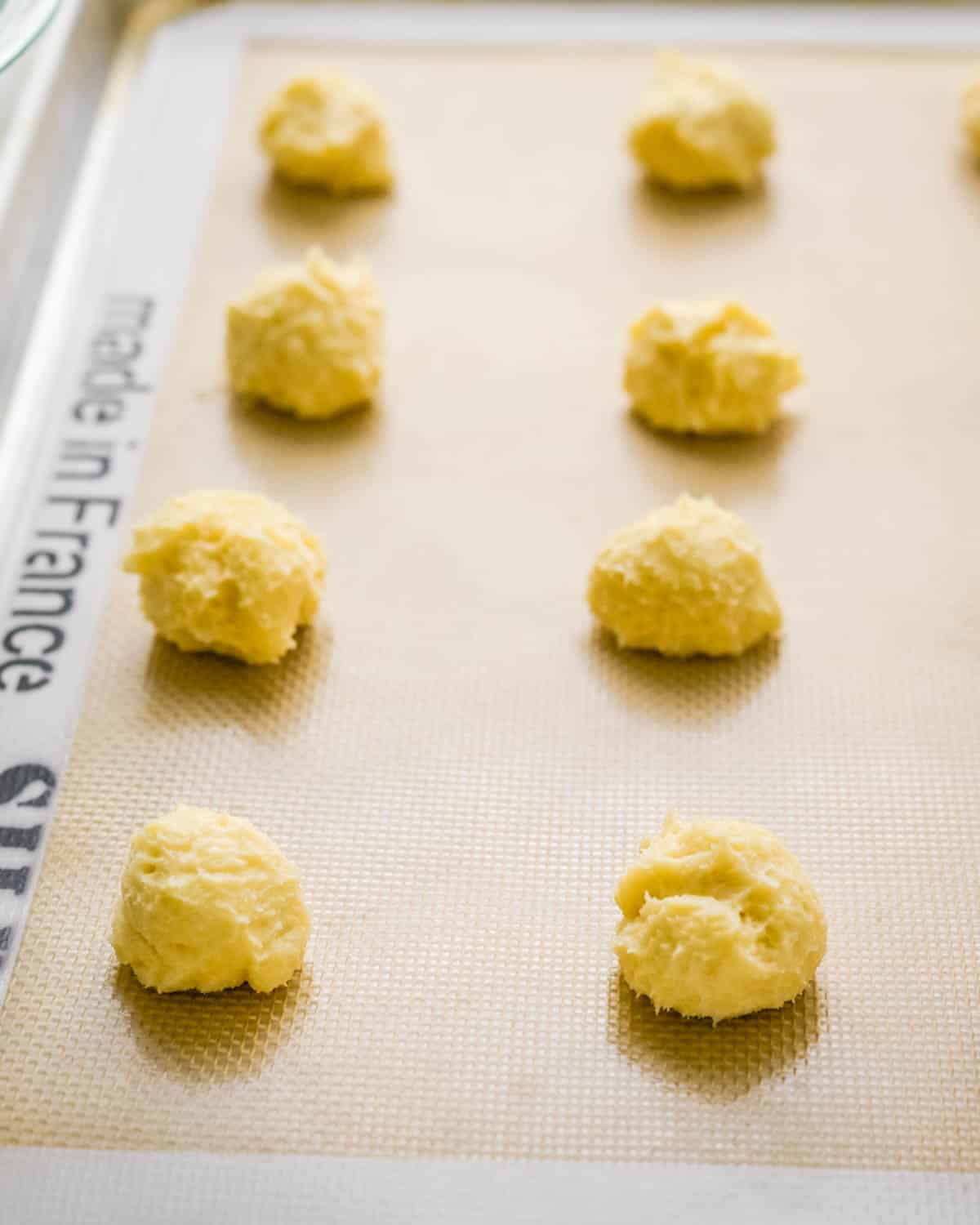 Scooping rounds of cookie dough onto a baking sheet.