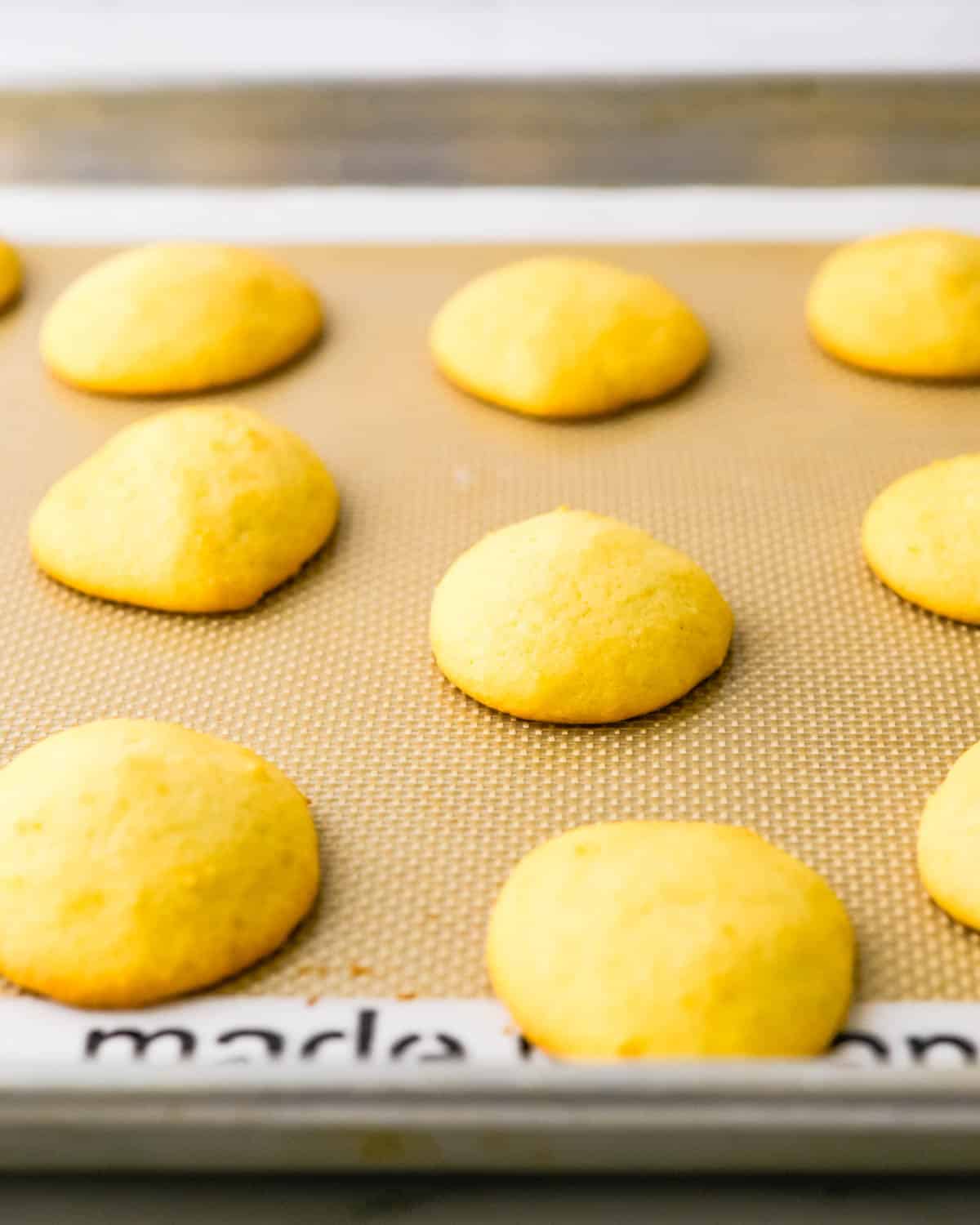 Baked lemon ricotta cookies on a baking sheet.