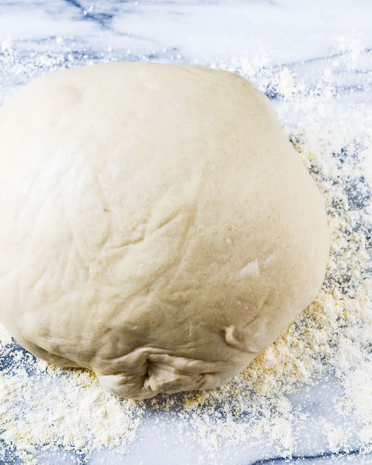 A ball of pizza dough on a marble board.