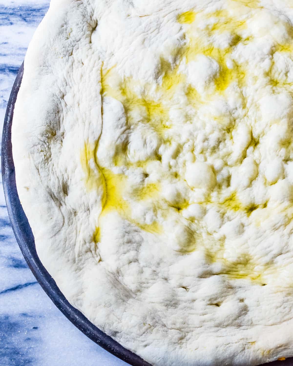 Drizzling the pizza dough with olive oil