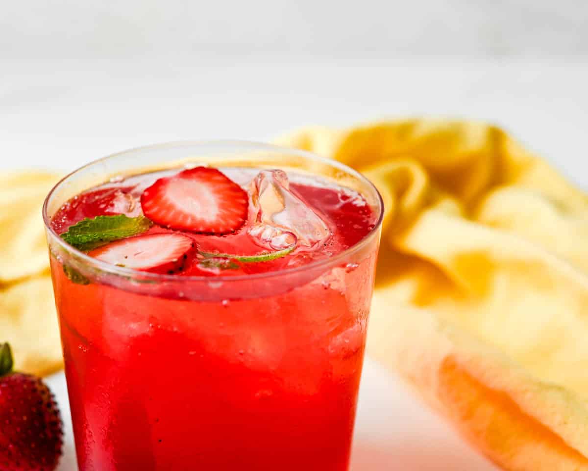 Slices of fresh strawberry float on top of the lemonade.