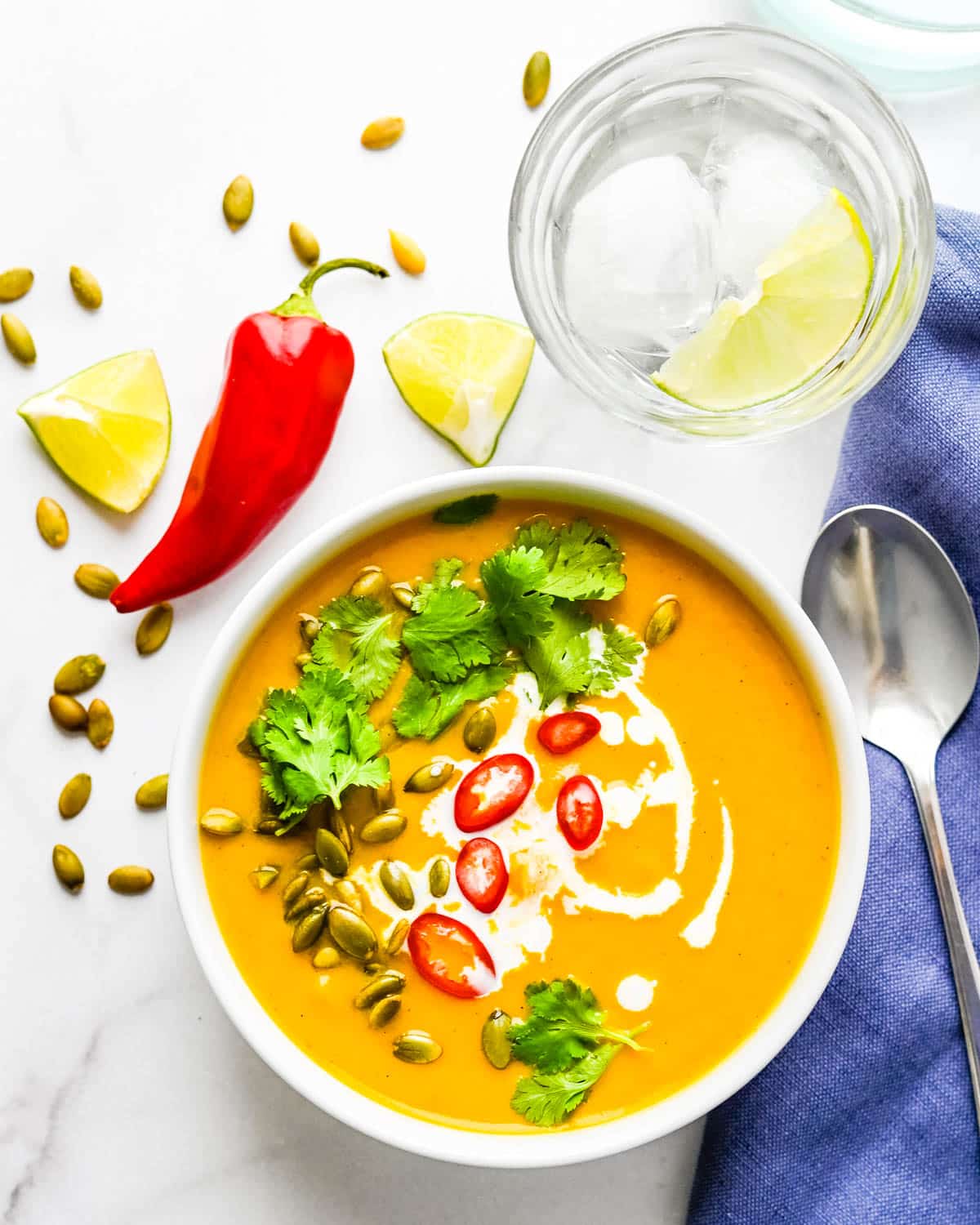 A bowl of thai pumpkin soup with pepitas and red chilies.