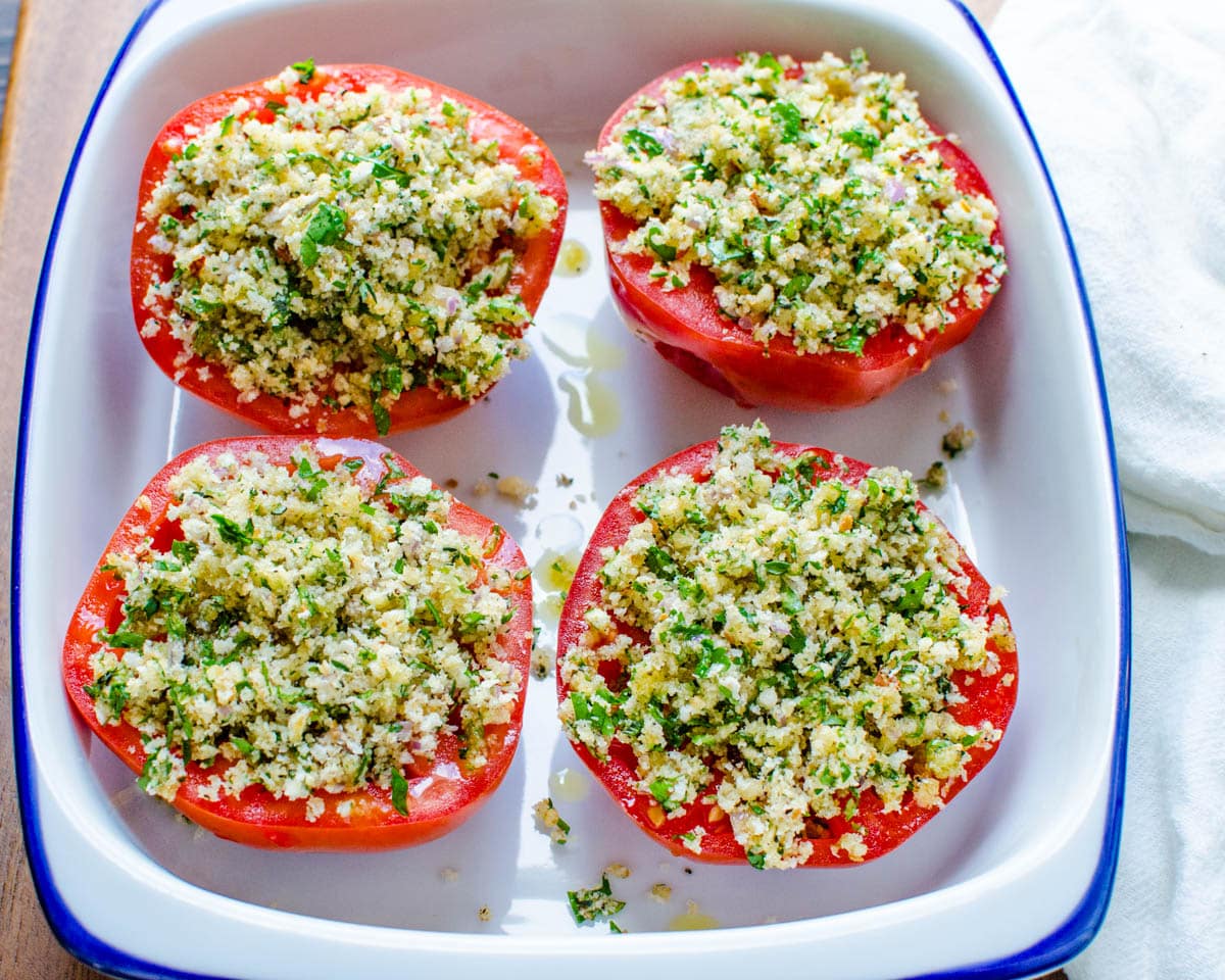 Arranging the tomatoes with breadcrumbs in a baking dish to bake.