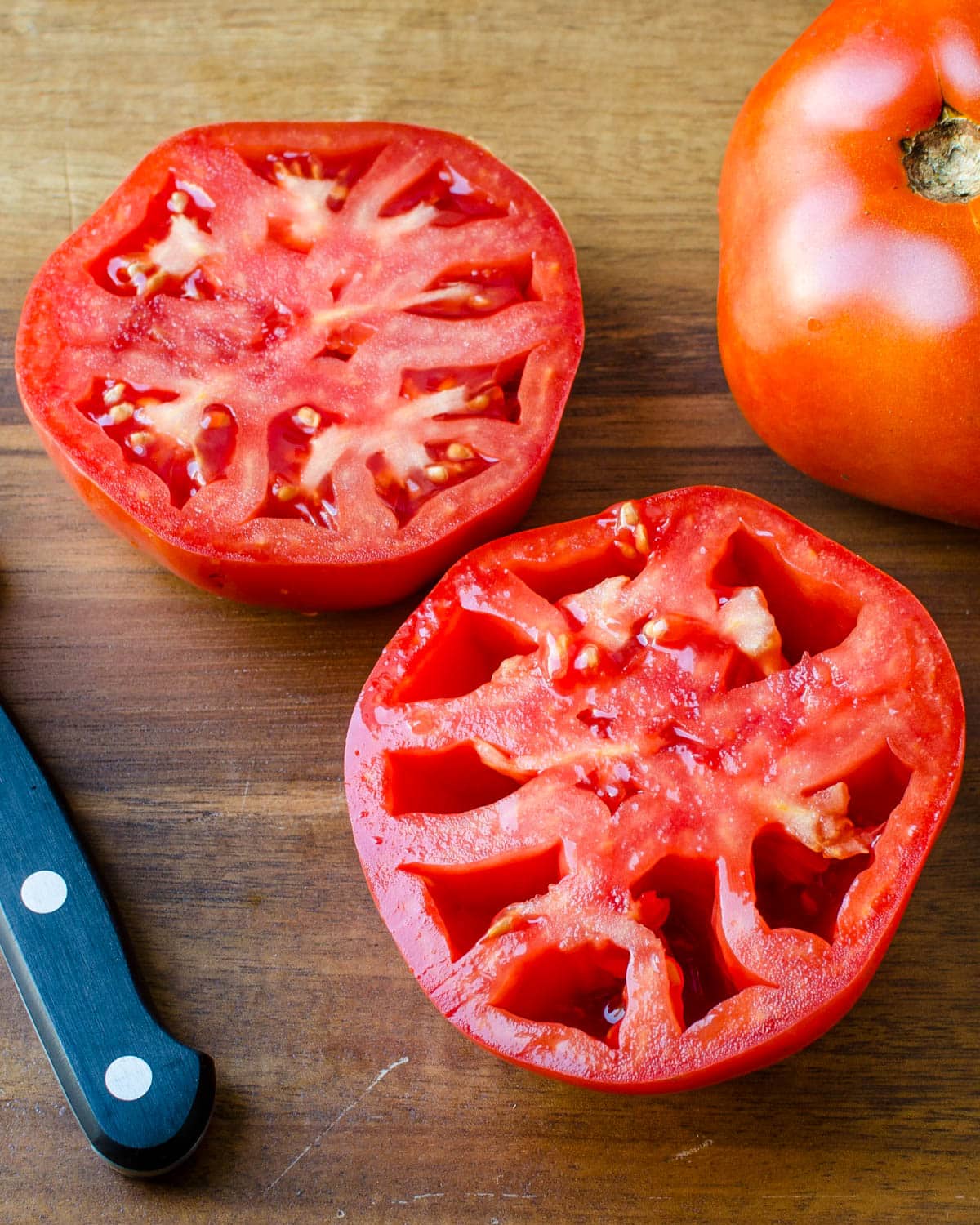 Slicing a tomato in half and deseeding it.