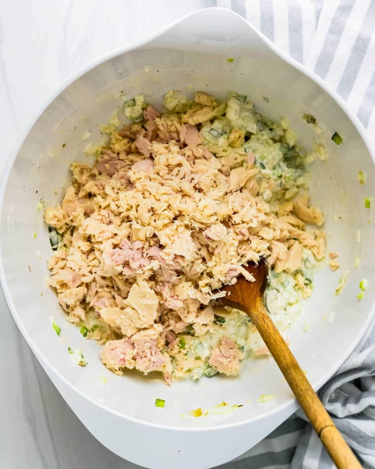 Adding flaked tuna fish to the mayonnaise mixture.