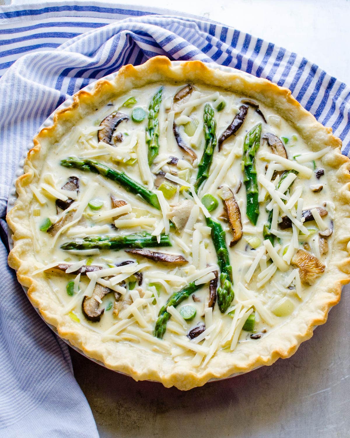 Filling the crust with the egg custard and arranging asparagus spears on top.