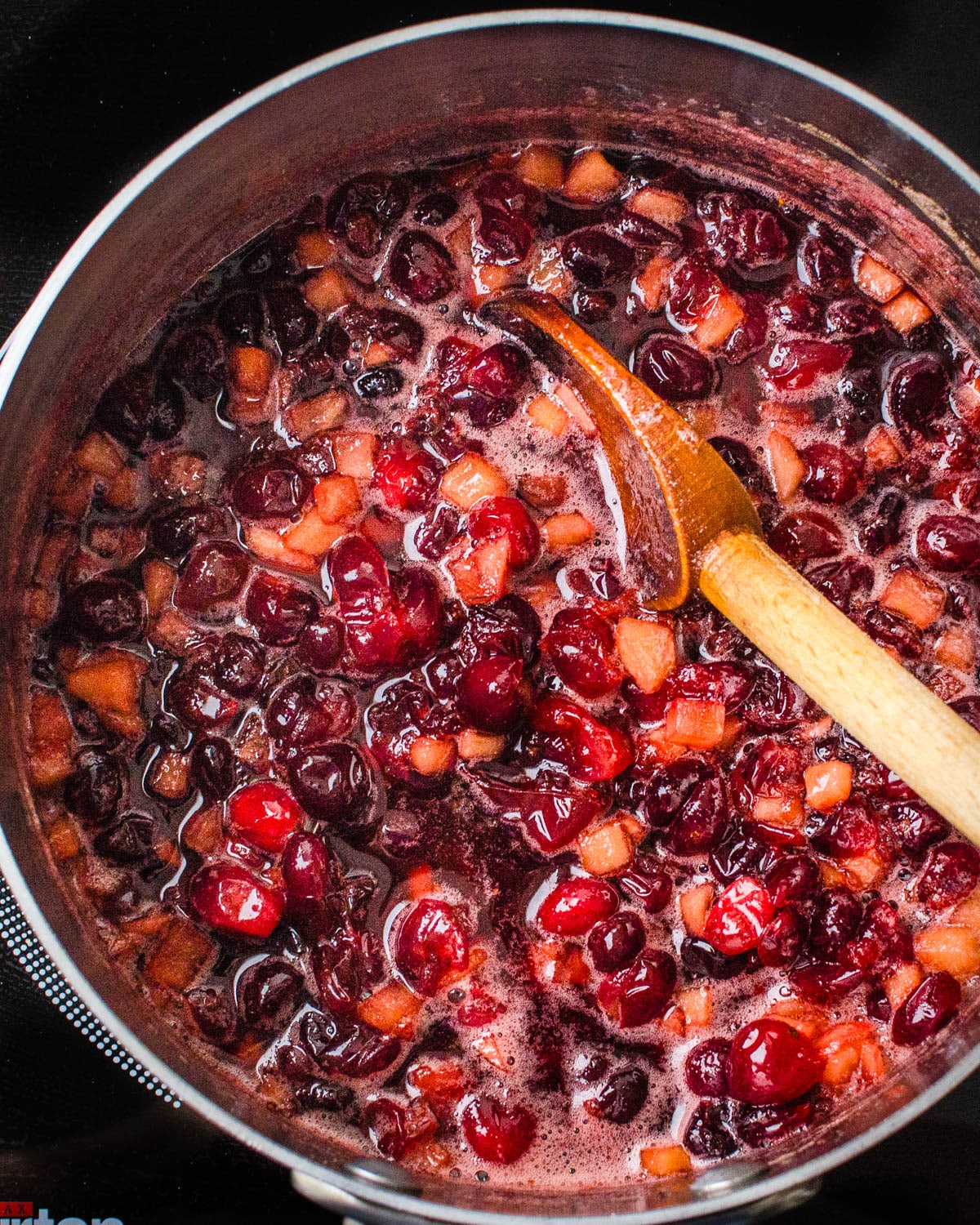 Cooking the apples and cranberries until the berries burst.