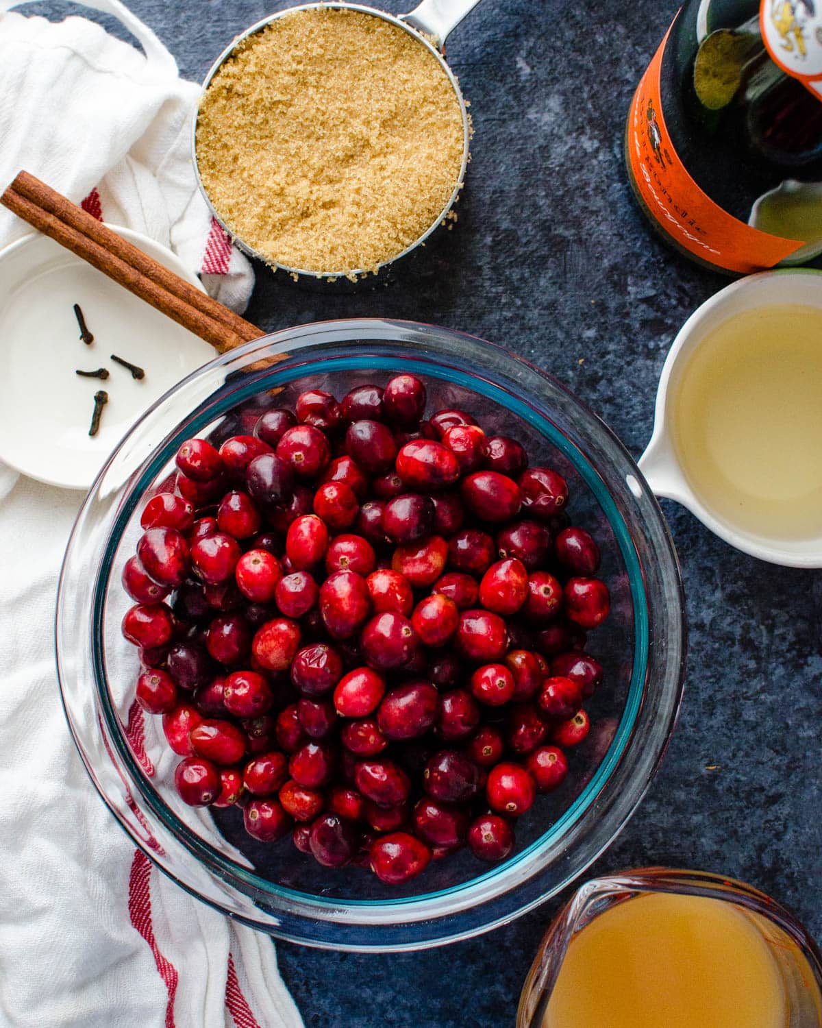 A bowl of cranberries with brown sugar, cloves, cinnamon, wine and cider.