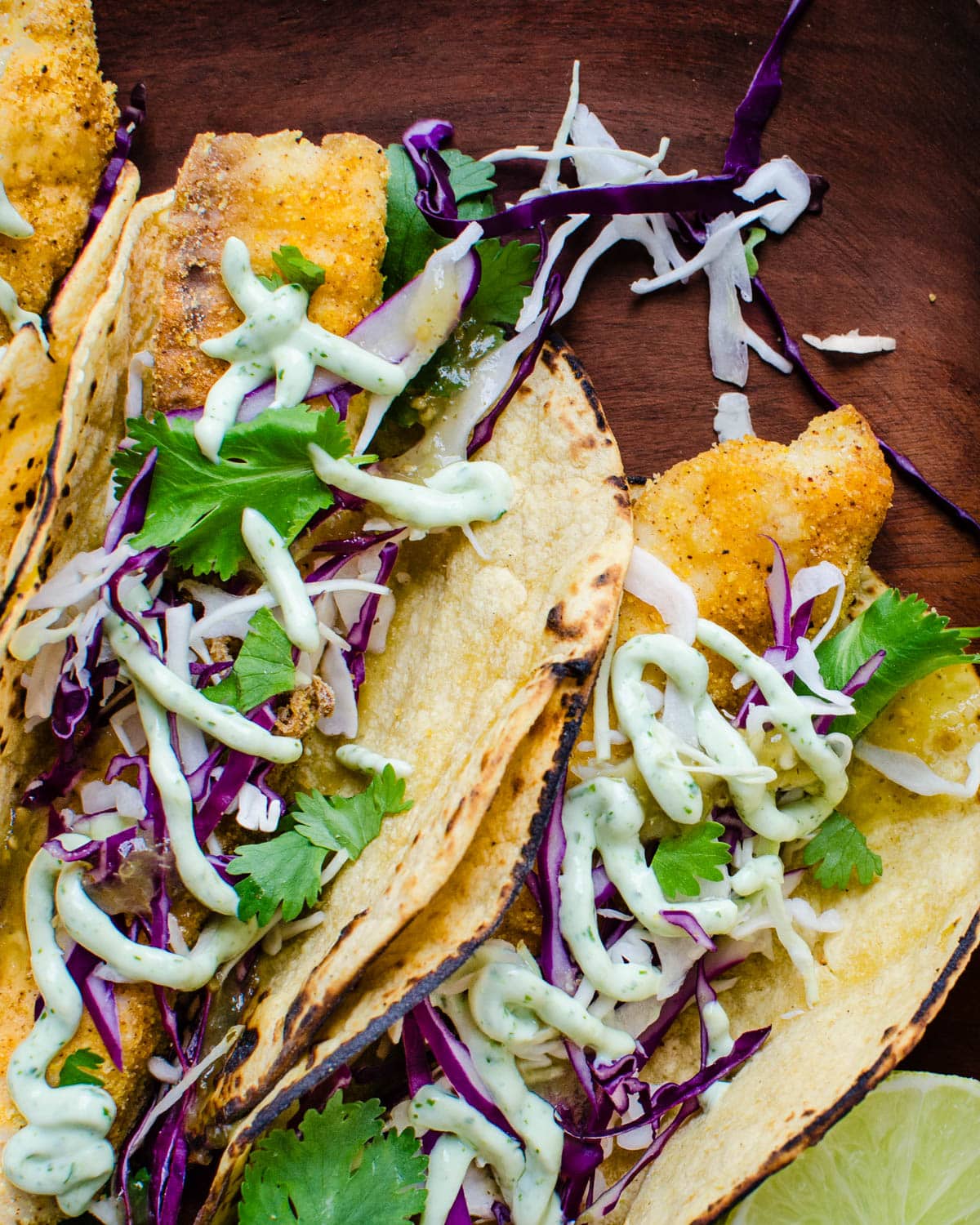 Serving three dressed fish tacos with crema and cilantro. 