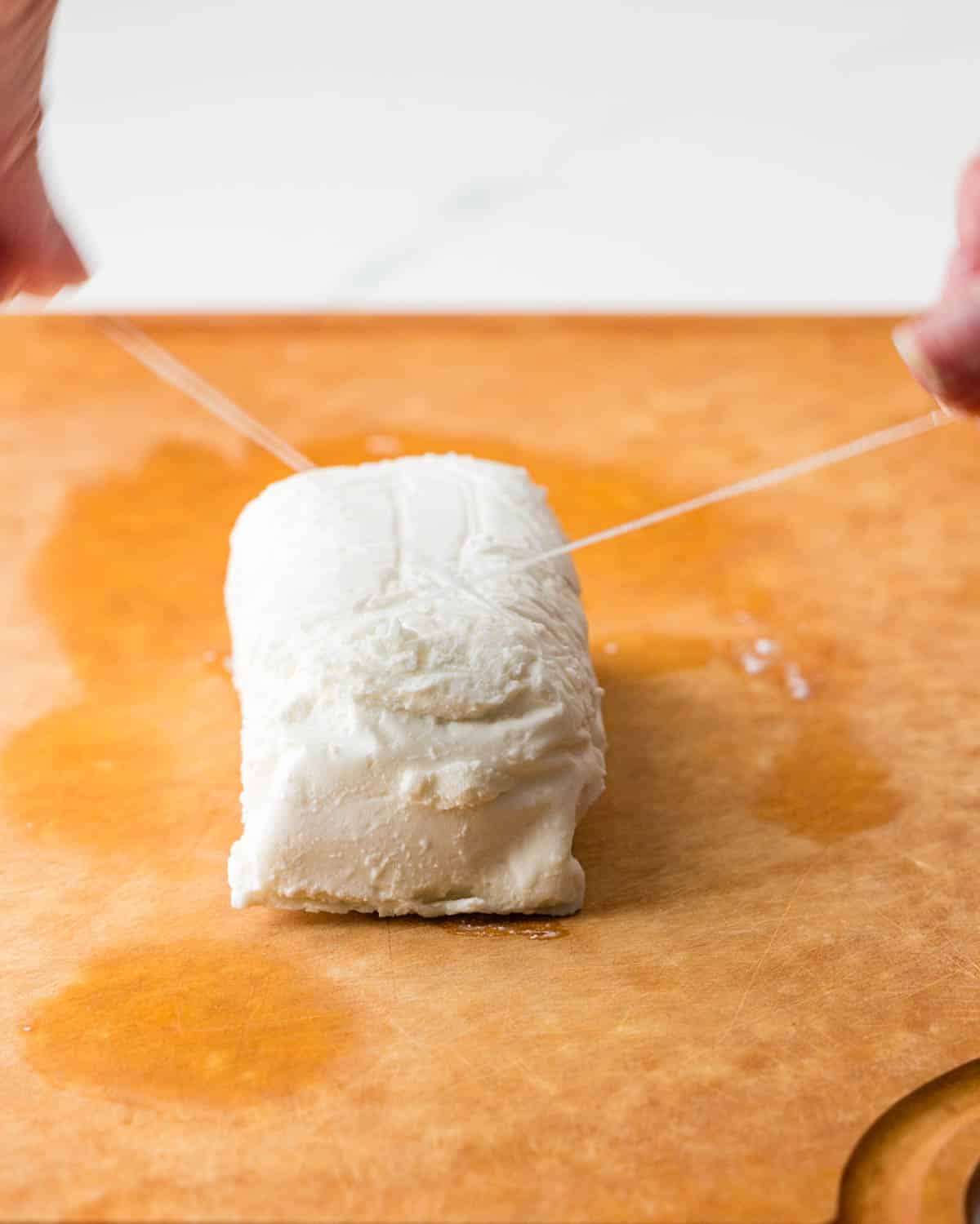 Slicing goat cheese with a piece of dent