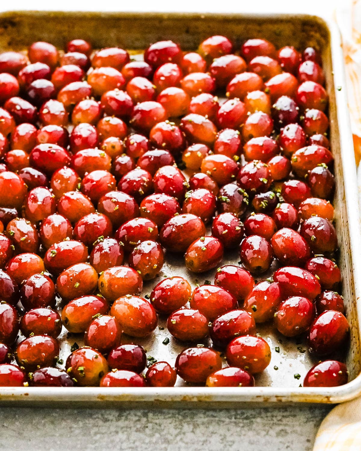 Roasting grapes on a sheet pan with oil and rosemary.